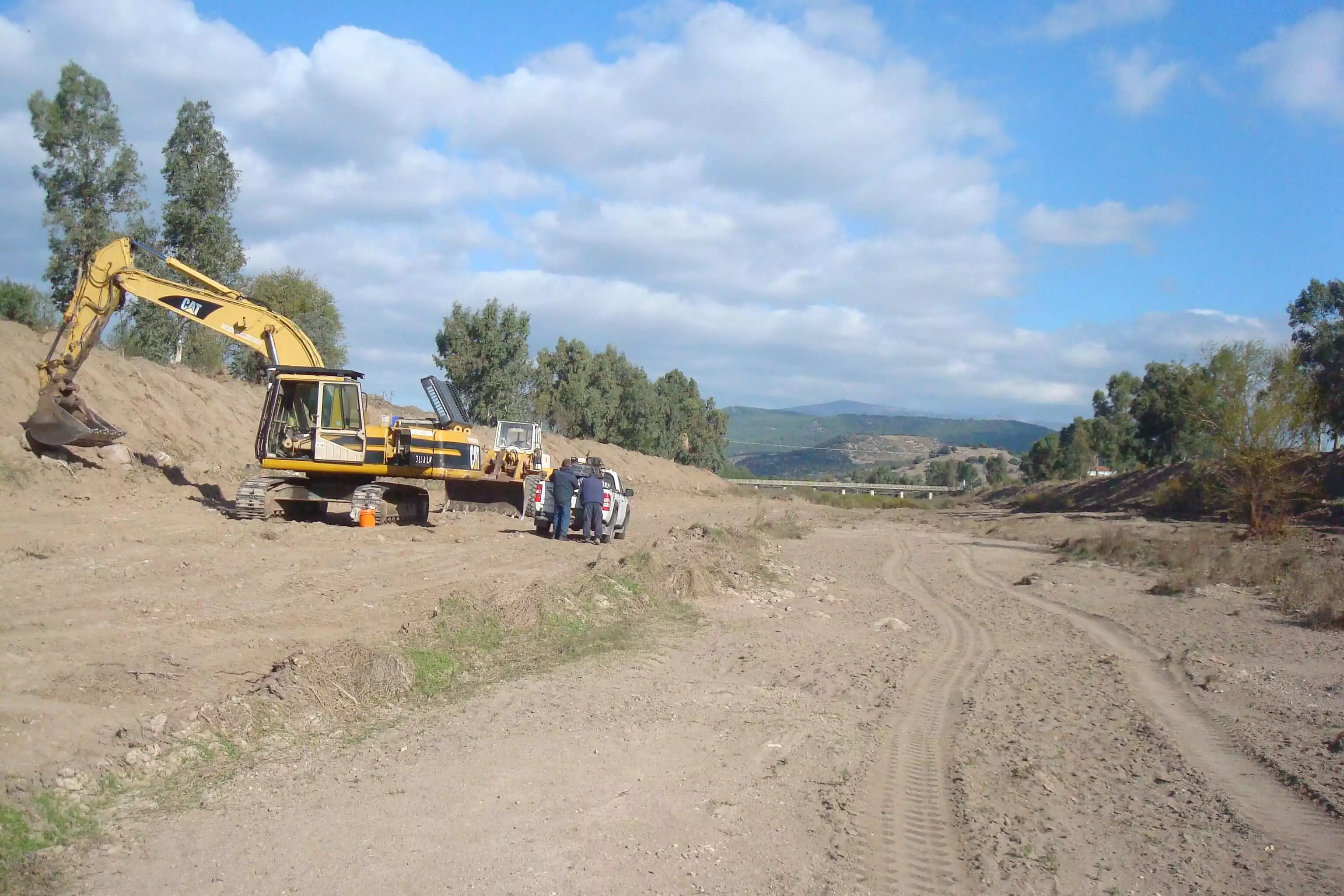 Καθαρισμένος χείμαρος χωρίς ξερά, χωρίς επιπλέον πρανοί και χωρίς φερτά υλικά. Εντός του χειμάρου και στην άκρη του απεικονίζεται ένας εκσκαφέας τύπου Caterpillar, ακριβώς στο πλάι του βρίσκεται εργατικό προσωπικό μαζί με ένα αγροτικό όχημα. Στο βάθος του χειμάρου φαίνεται μια γέφυρα.